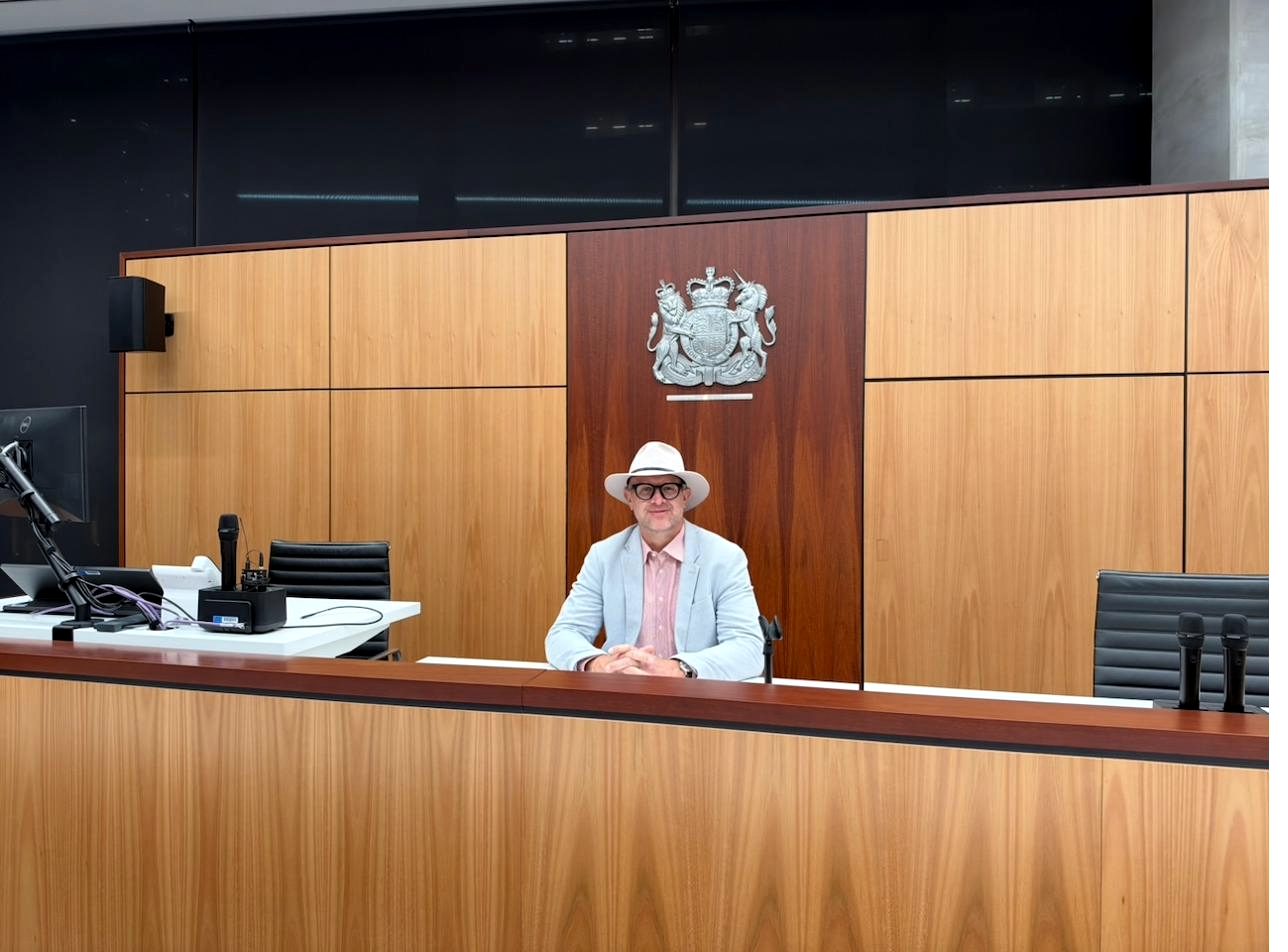 Paul Faix at the bench of a moot court at ECU City Campus