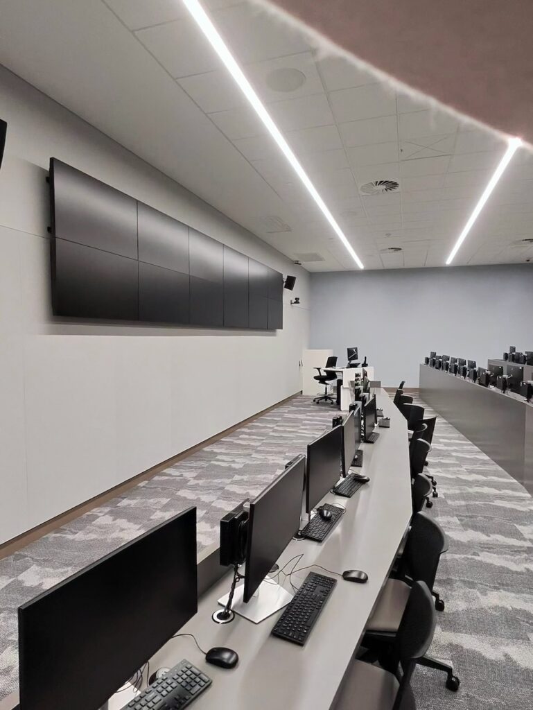 Rows of monitor workstations facing a video wall inside the Security Operations Centre at ECU City Campus